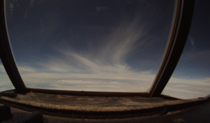 View out the center window of C-130 of light wispy clouds